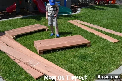 Two people working together to attach a long board to the short sides, squaring the corner.
