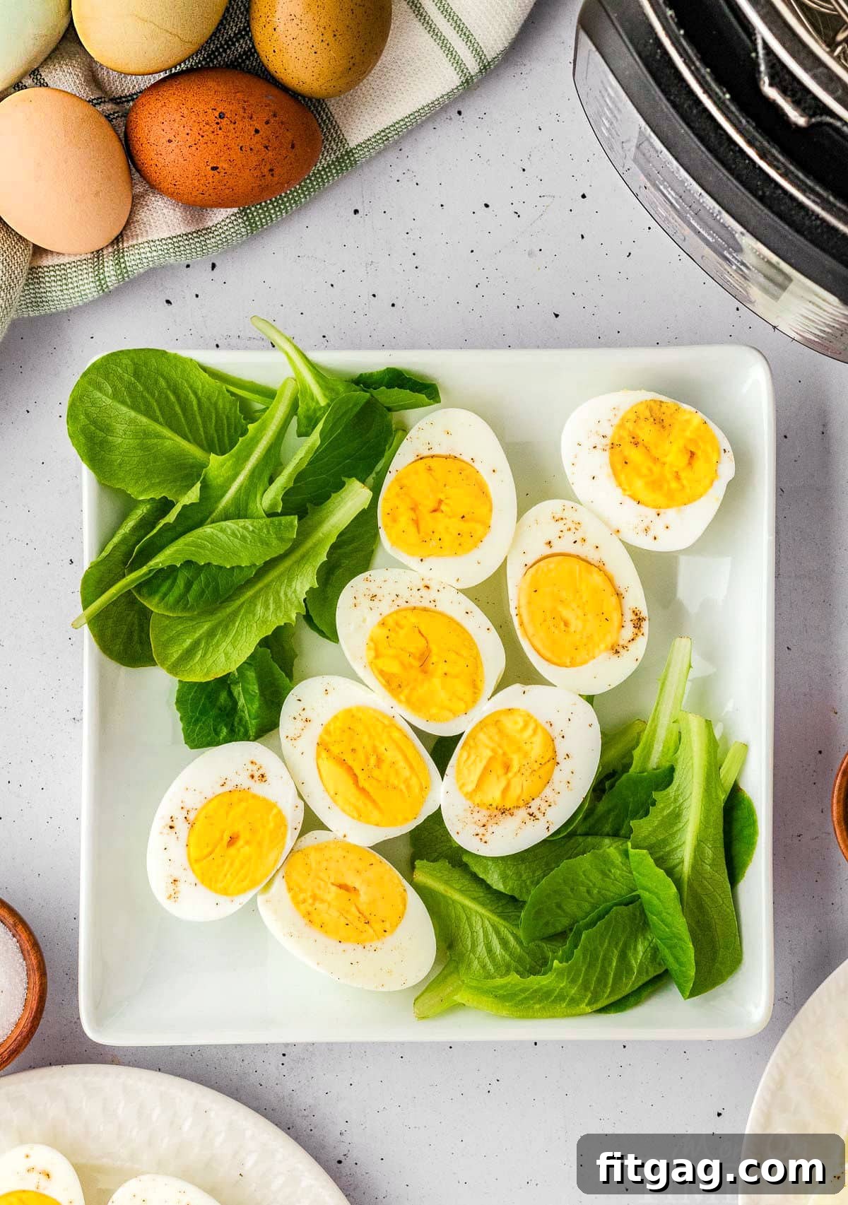 Hard boiled eggs on a bed of spinach on a white plate.