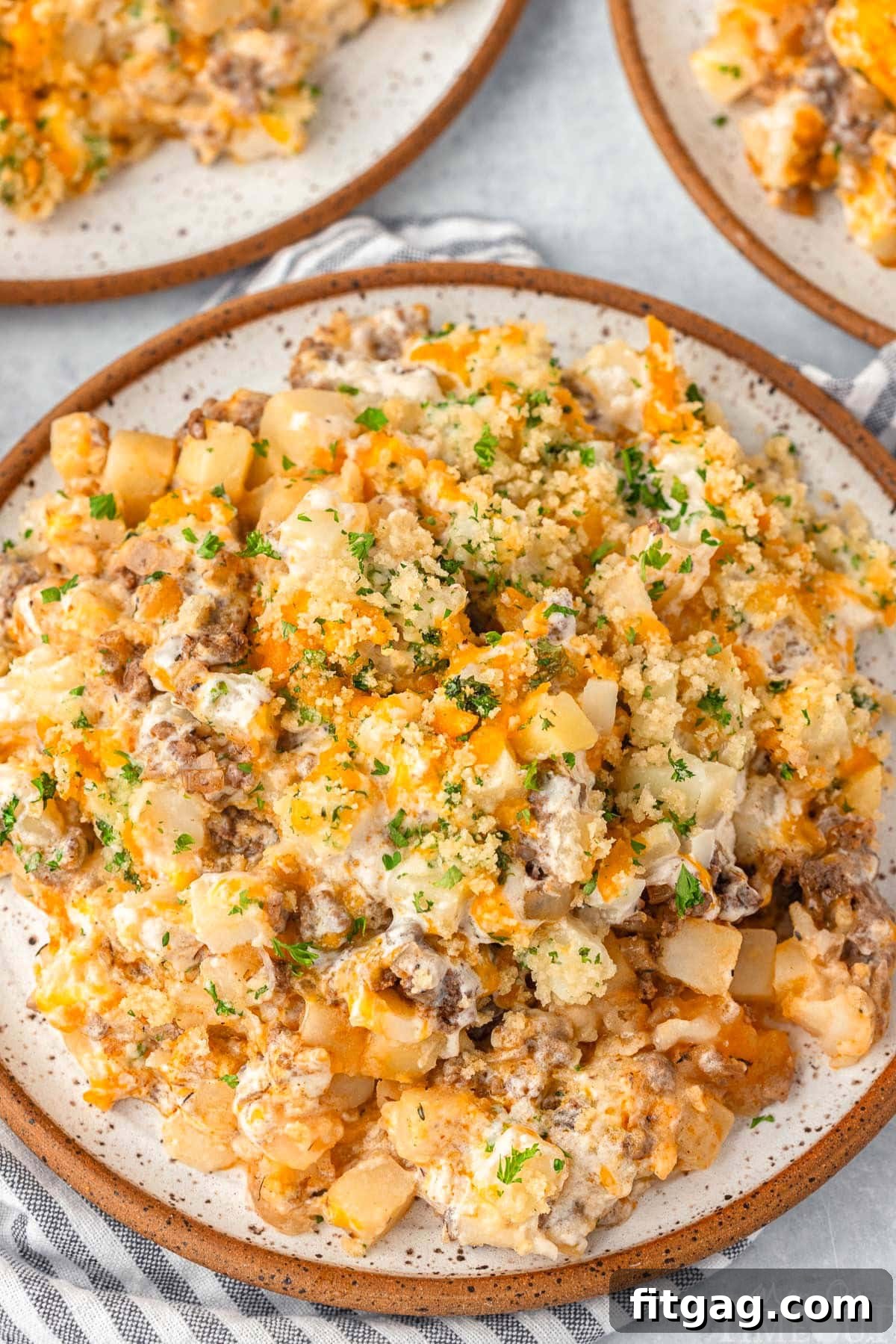Hearty Beef Bake 2 Top down view of a serving of cheesy ground beef and potato casserole on a plate, garnished with chopped parsley.