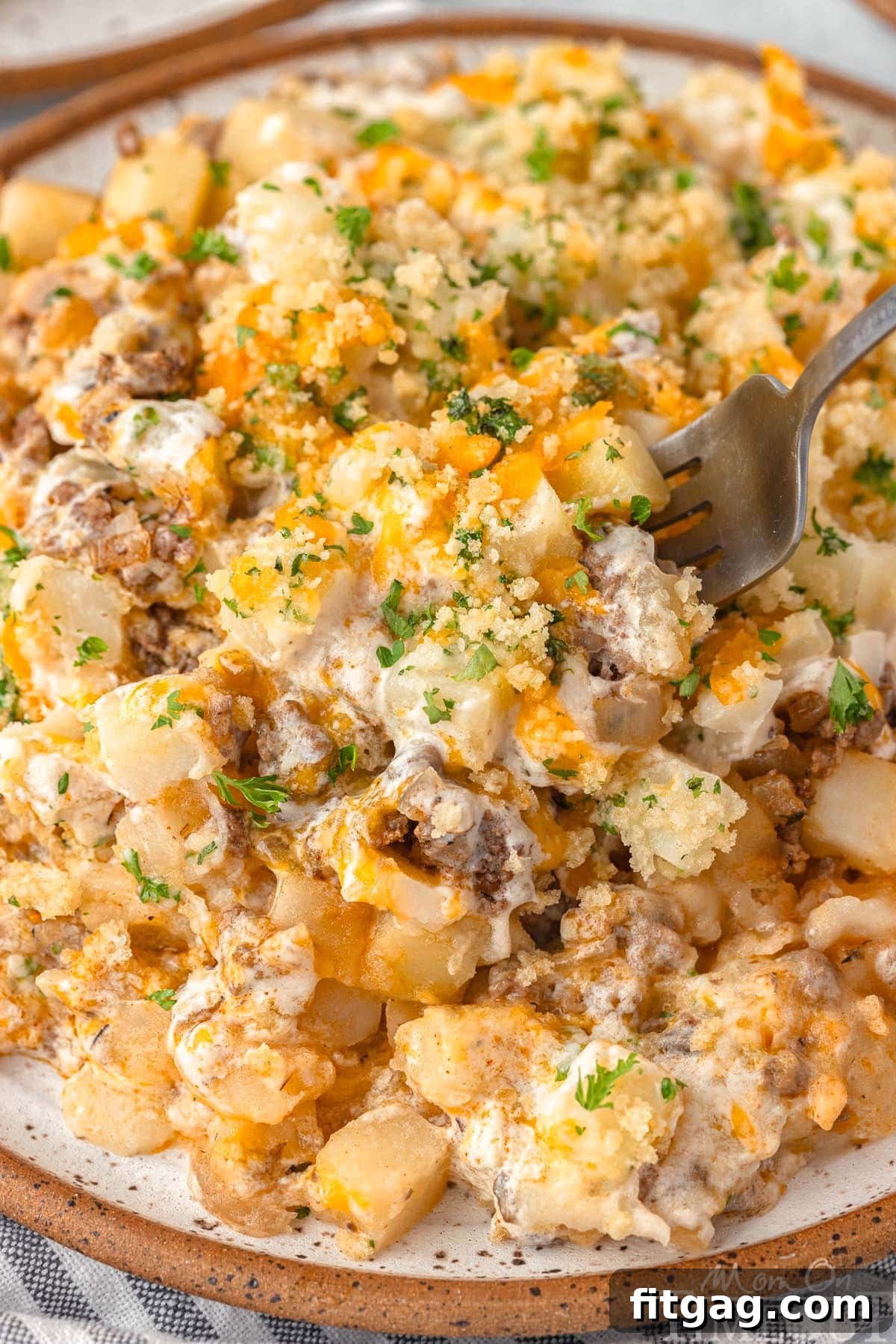Hearty Beef Bake 4 A close-up of the cheesy ground beef and potato casserole served on a plate, with a fork digging in.