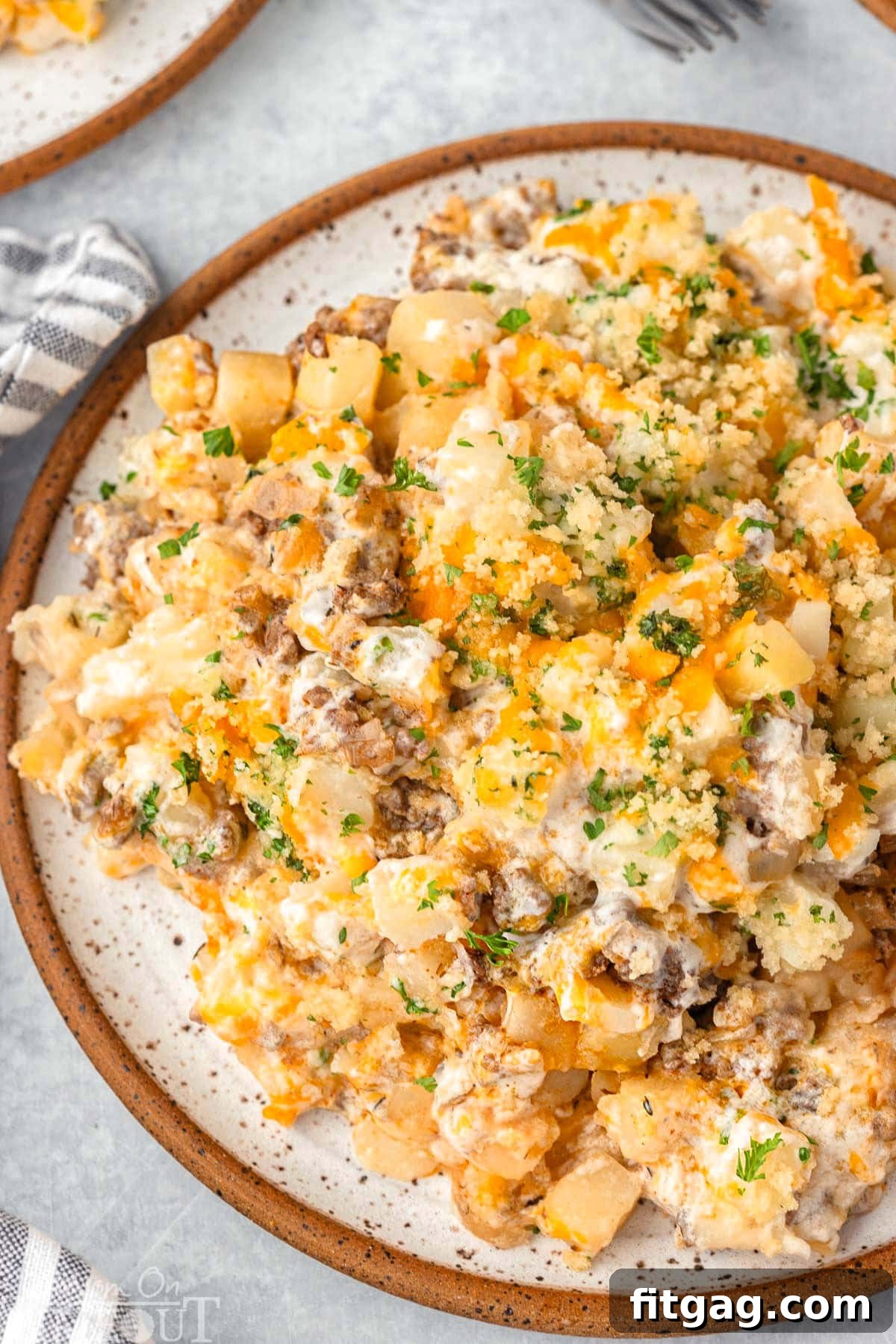 Hearty Beef Bake 8 Top down view of a single serving of easy ground beef casserole plated on a round inner plate and topped with chopped parsley.