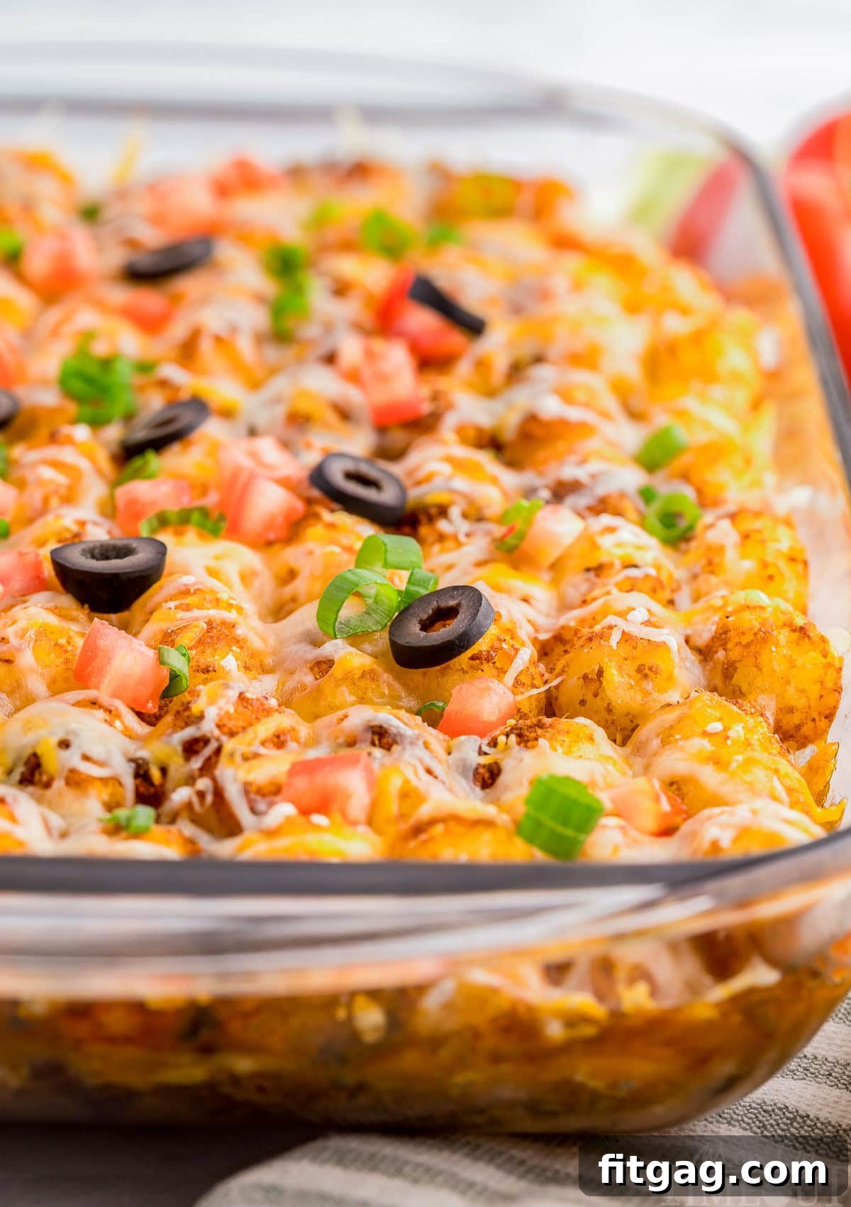 A close up shot of mexican tater tot casserole in a glass pan.