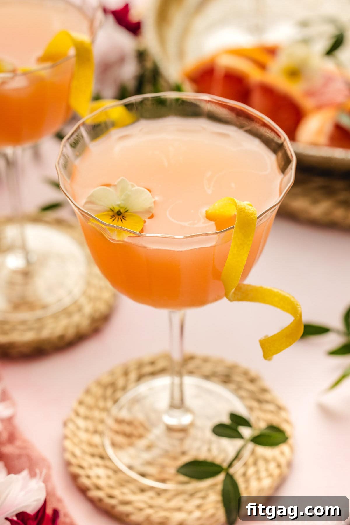 A vibrant French Blonde Cocktail served in an elegant coupe glass, garnished with fresh grapefruit and edible flowers, ready to be enjoyed.