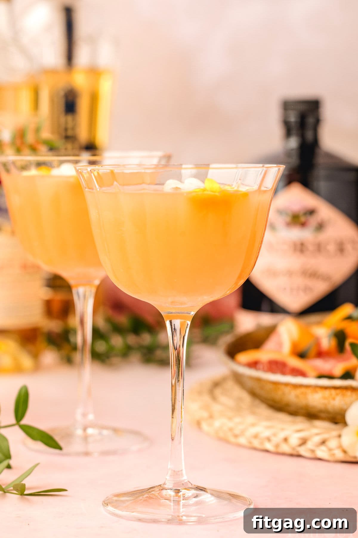 Two perfectly prepared French Blonde Cocktails in coupe glasses await, with the essential bottles of gin, Lillet Blanc, and St-Germain artistically arranged in the soft-focused background.