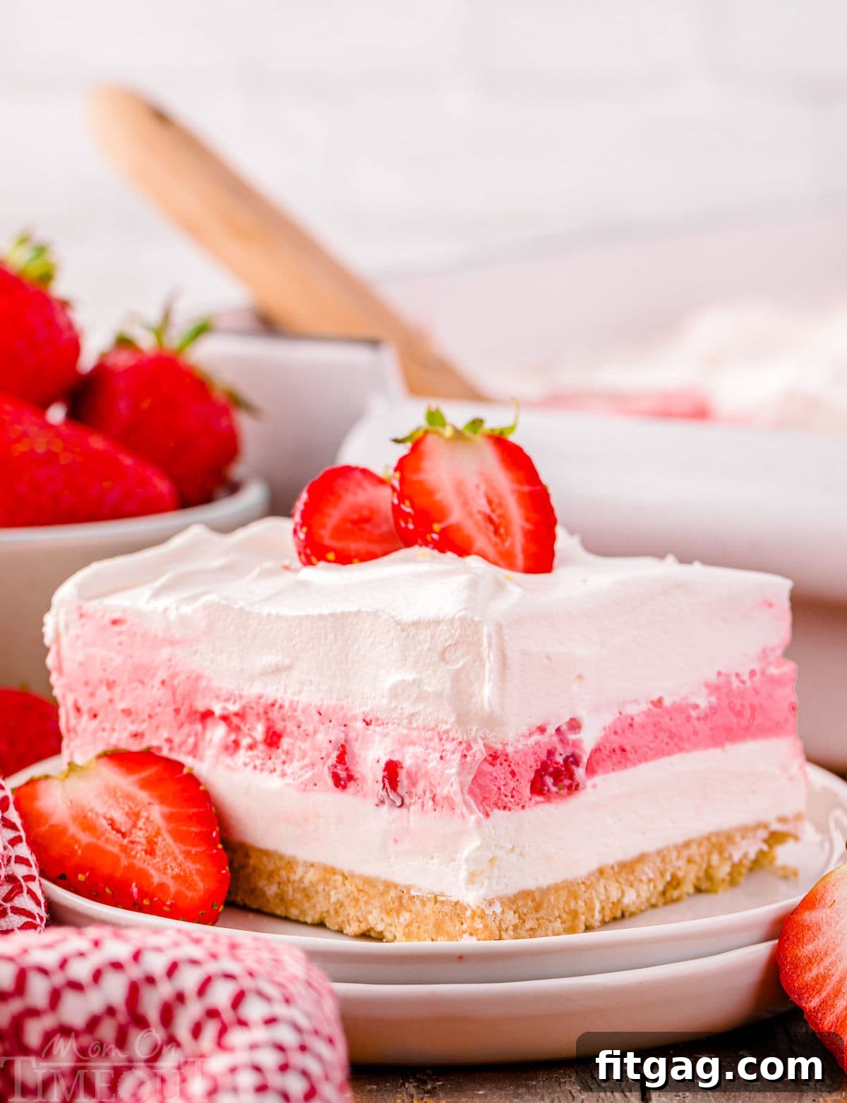 A pristine slice of strawberry lasagna on a white plate, beautifully showcasing its distinct and vibrant layers, ready to be enjoyed.