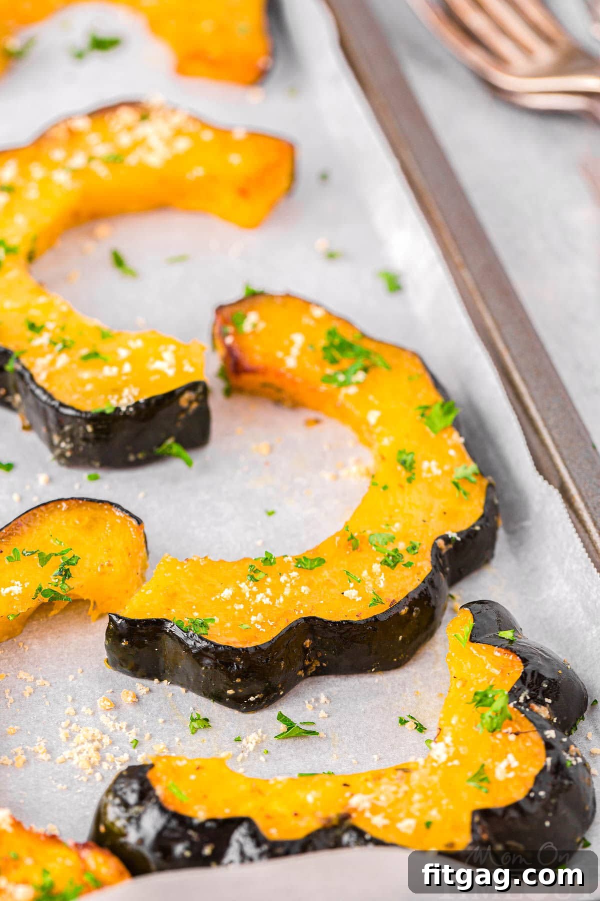 Roasted acorn squash wedges laid out neatly on a parchment-lined baking sheet, ready to be served.