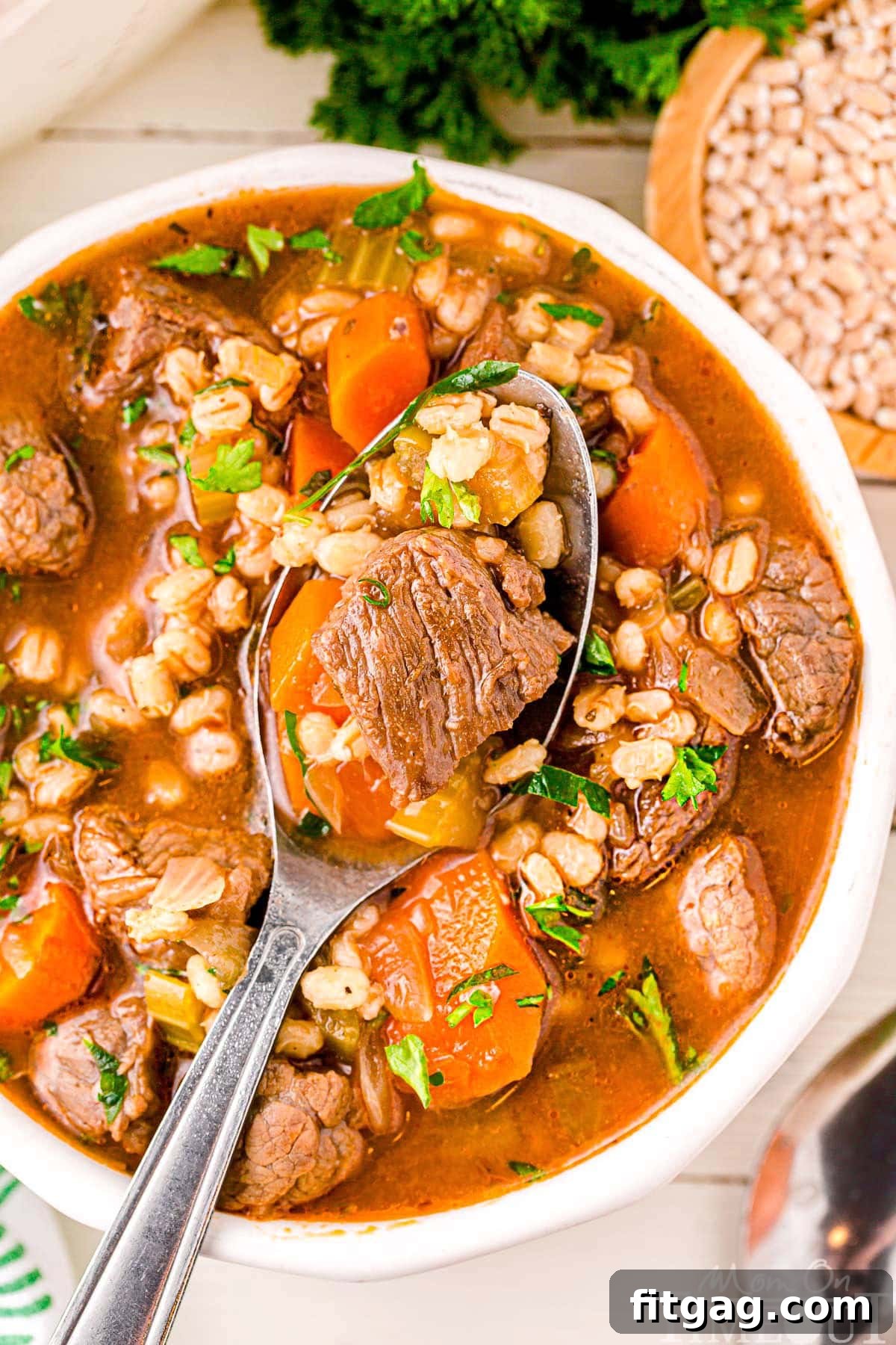 Hearty Beef and Barley Comfort Bowl 4 A top down view of a spoon in a bowl of beef and barley soup.