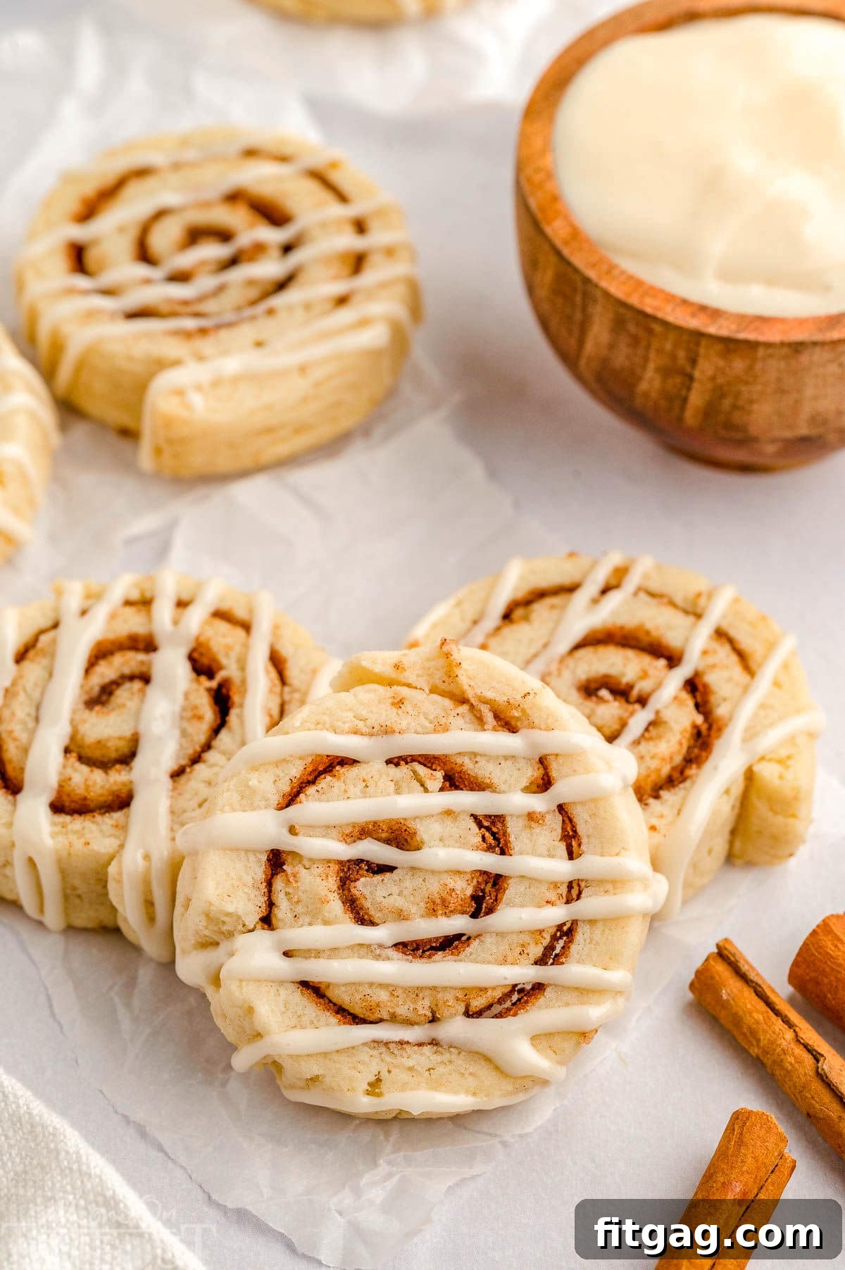 Cinnamon Swirl Delights 4 Cinnamon roll cookies laying on a piece of parchment paper.