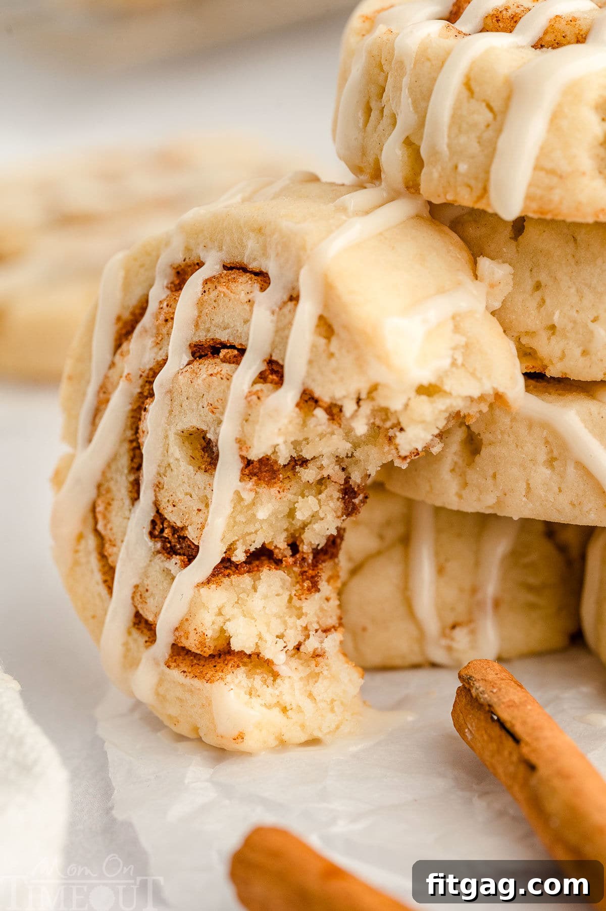 Cinnamon Swirl Delights 7 A shot of a cinnamon roll cookie with a bite take out of it leaning against a stack of more cinnamon roll cookies.
