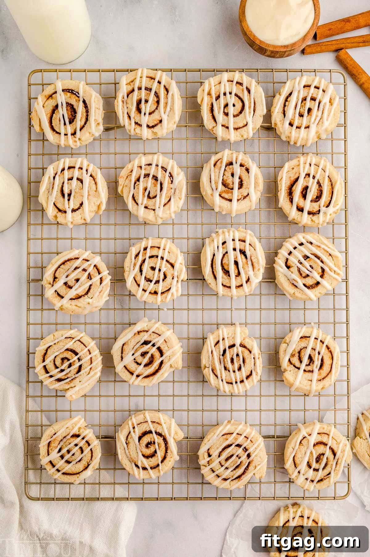 Cinnamon Swirl Delights 8 Top down view of cinnamon roll cookies recipe on wire rack drizzled with cream cheese icing.