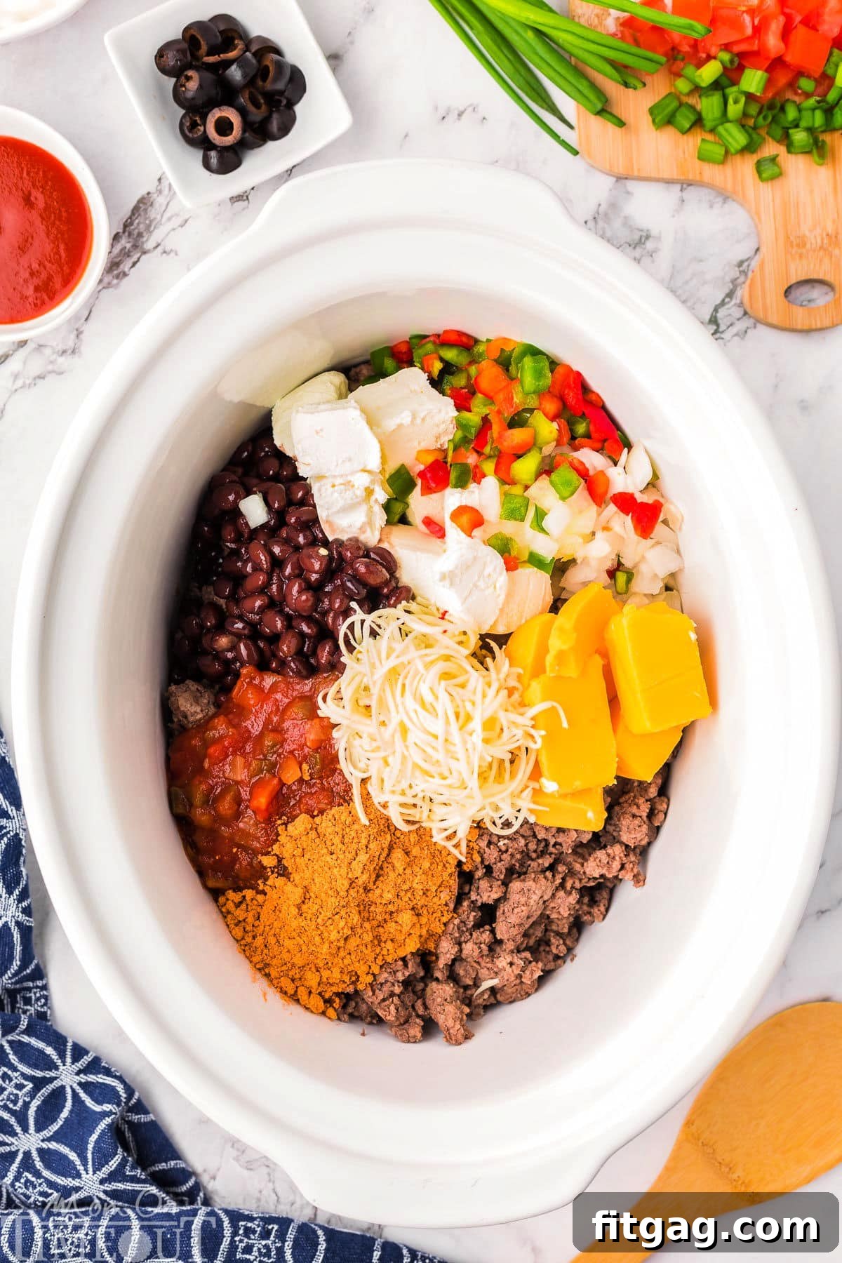 Warm and Cheesy Slow Cooker Taco Dip 3 Crockpot taco dip ingredients in a slow cooker.