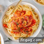 Slow Cooker Chicken Cacciatore on a bed of pasta on a white plate.