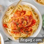 Slow Cooker Chicken Cacciatore on a bed of pasta on a white plate.