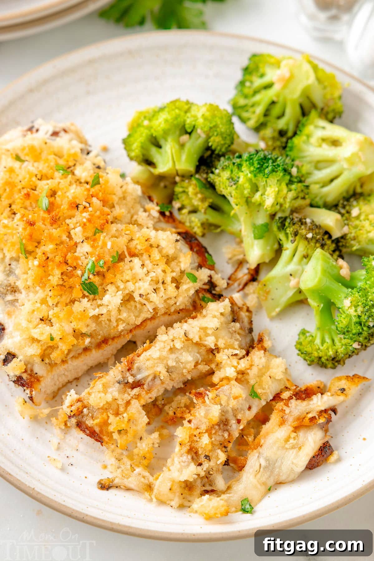 Longhorn Parmesan crusted chicken on a white plate next to a side of broccoli.