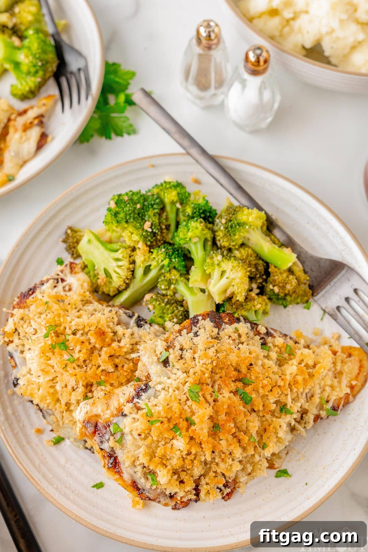 Longhorn Parmesan crusted chicken on a white plate next to a side of broccoli.