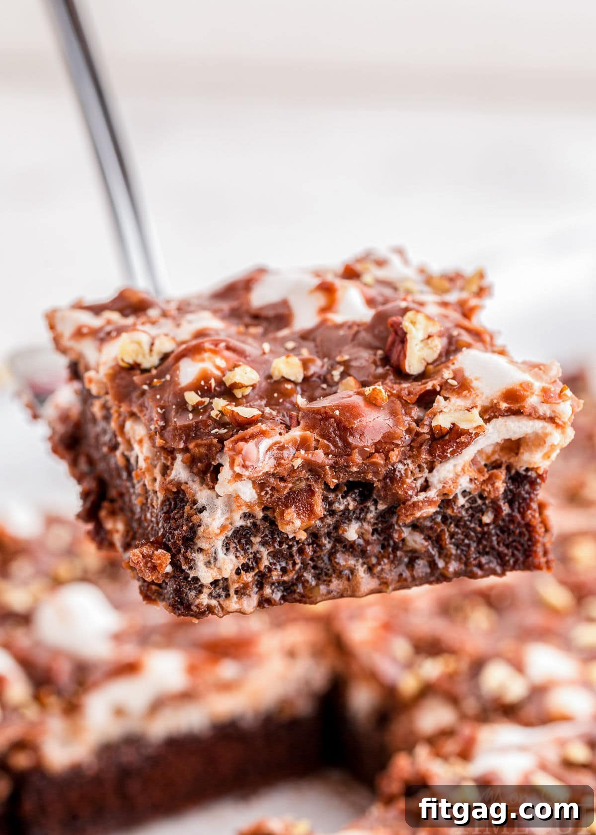 Riverbend Chocolate Dream 2 A glorious slice of Mississippi Mud Cake, showcasing its distinct layers of moist chocolate cake, gooey marshmallows, and rich chocolate pecan frosting, being elegantly lifted from the pan with a server, ready to be devoured.
