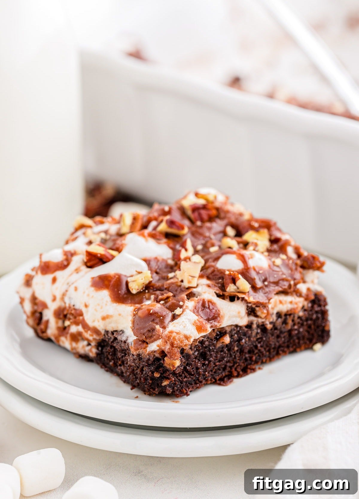 Riverbend Chocolate Dream 8 A perfectly portioned piece of Mississippi Mud Cake artfully presented on a pristine round white dessert plate, elegantly stacked upon another plate, highlighting its distinct layers and tempting texture.