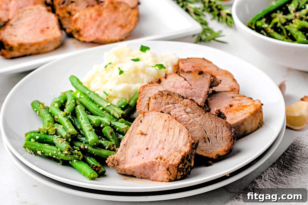 Perfectly Tender Air Fryer Pork Tenderloin 4 A dinner plate featuring slices of air fryer pork tenderloin alongside green beans and creamy mashed potatoes.