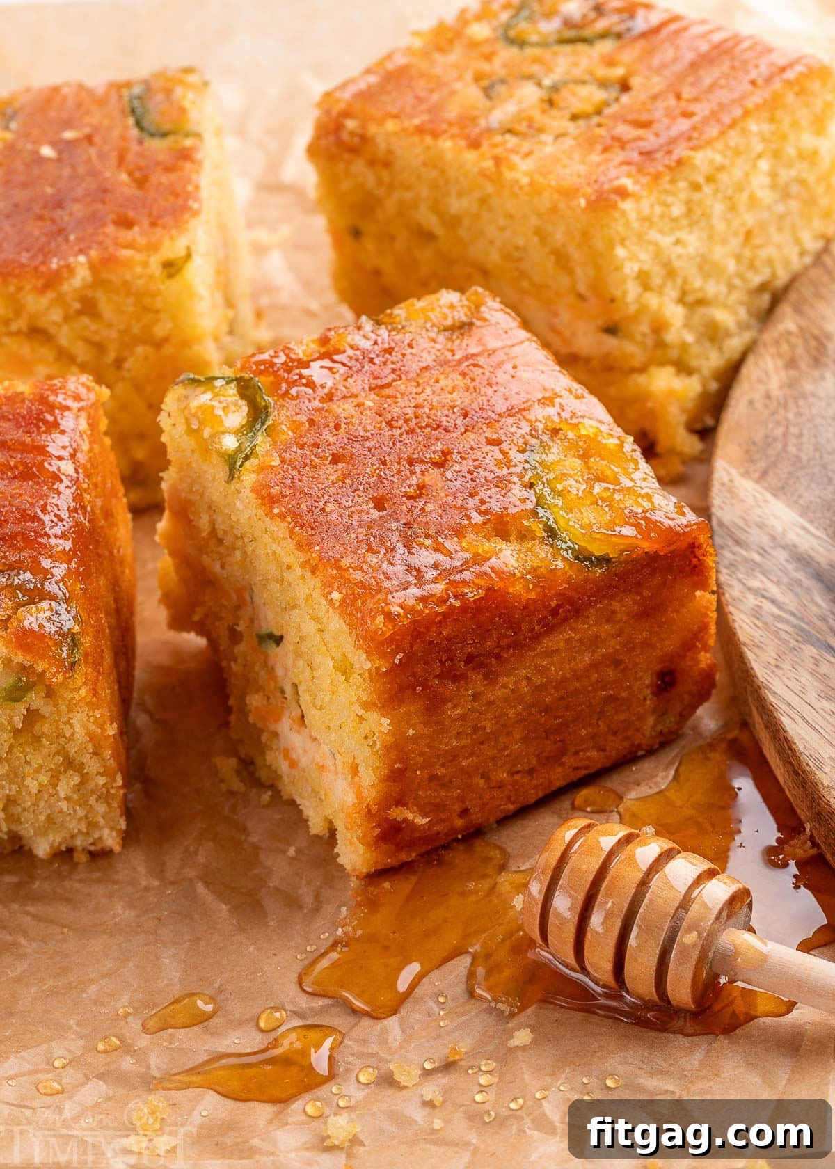 Spicy Cornbread Kick 2 Jalapeno Cornbread recipe cut into squares on parchment paper with honey dripping onto the paper.