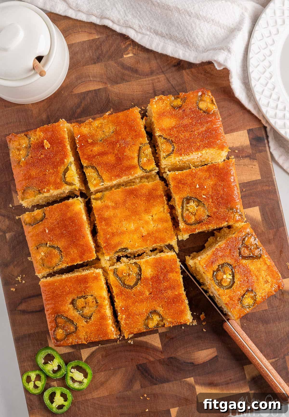 Spicy Cornbread Kick 3 Top down view of jalapeno cornbread on a wood cutting board cut into 9 squares.