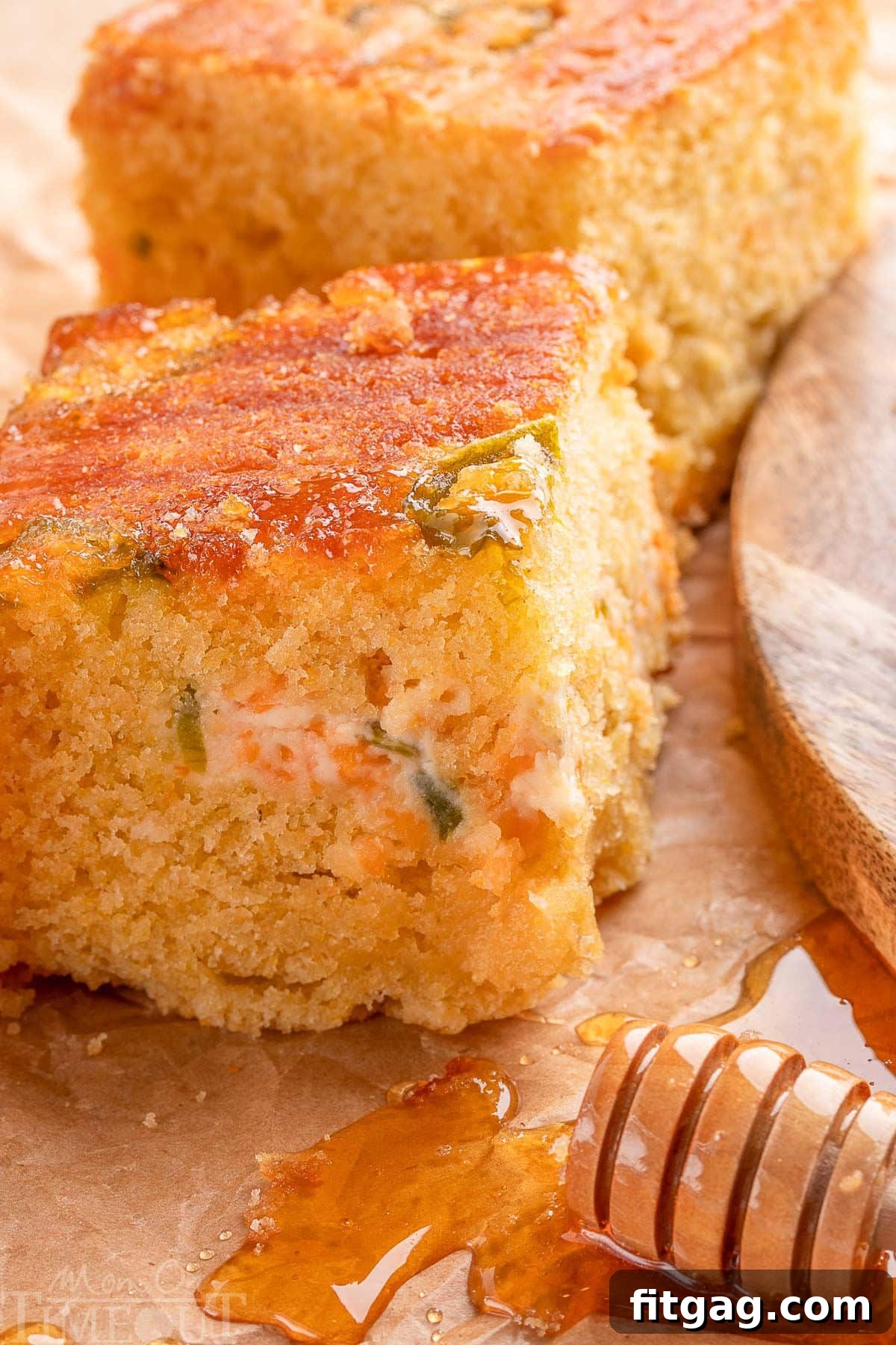 Spicy Cornbread Kick 7 Close look at jalapeno cornbread next to a wand of honey. The jalapeno popper layer in the center is clearly visible in the piece of cornbread.