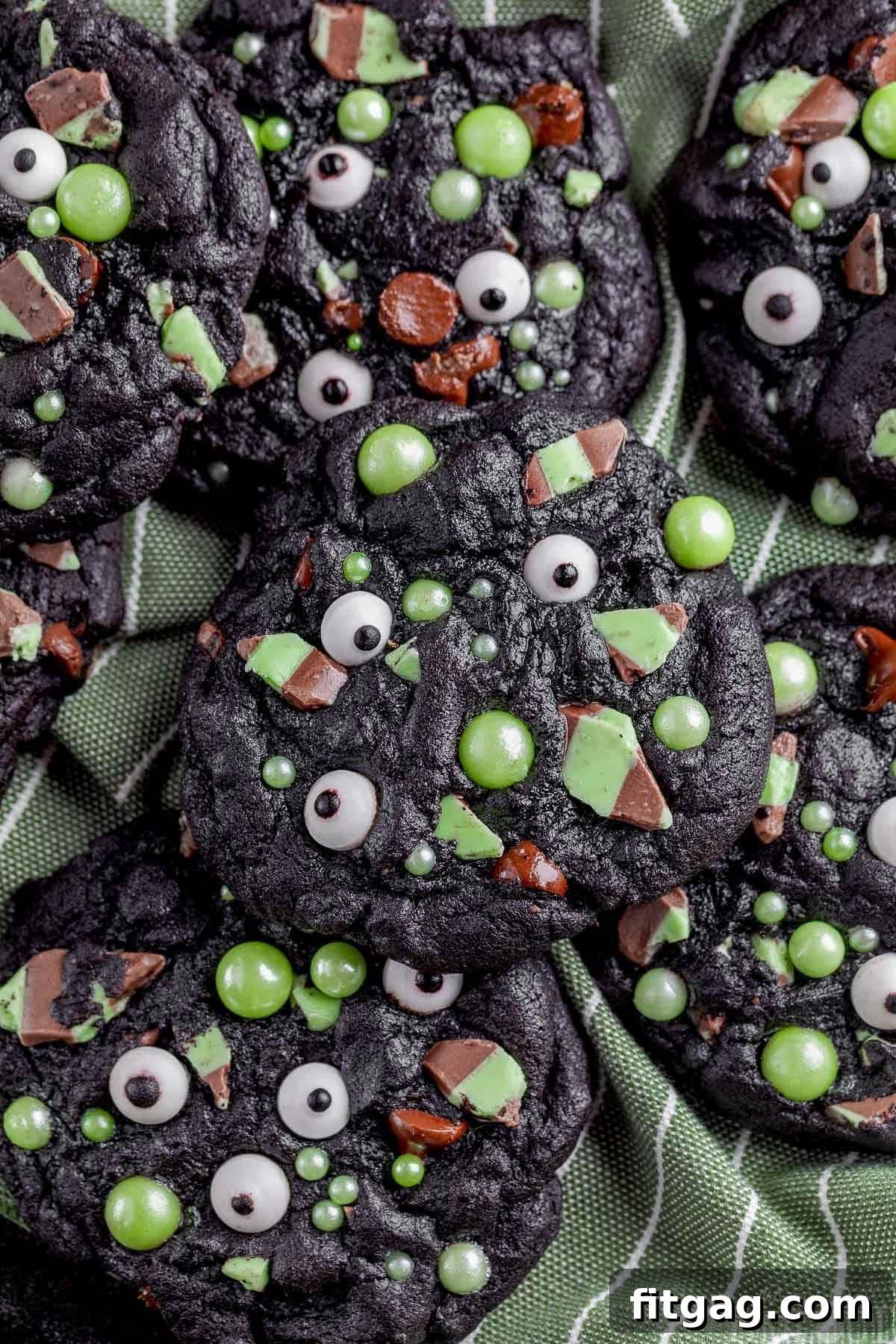 A pile of monster halloween cookies on a green cloth.