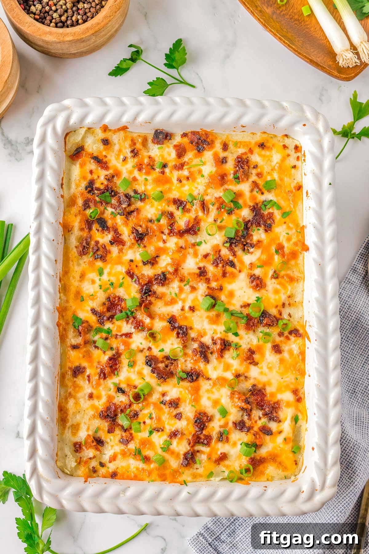 Homestyle Potato Perfection 7 Top down look at baked mashed potatoes in white casserole dish topped with cheese and bacon.