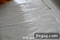 Spreading white glue onto wax paper with a popsicle stick