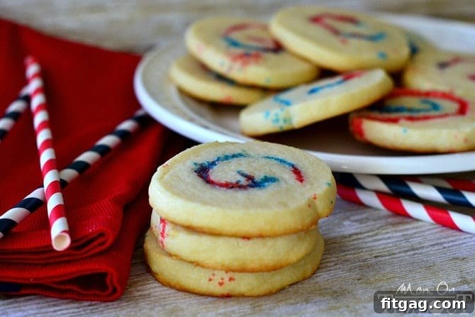 A plate of freshly baked Red, White, and Blue Sparkler Cookies, ready for a festive celebration. These spiraled sugar cookies are adorned with patriotic colors, making them ideal for the 4th of July, Memorial Day, or any American-themed gathering.