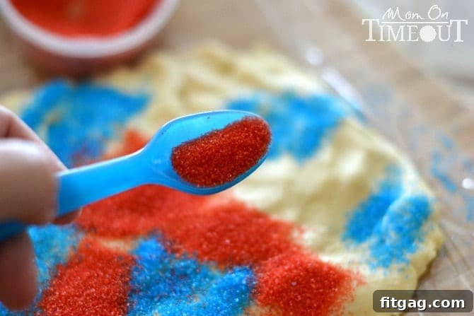 Step-by-step image showing colored red and blue sugars sprinkled in patches onto rolled-out cookie dough, illustrating the technique for creating patriotic sparkler cookies.