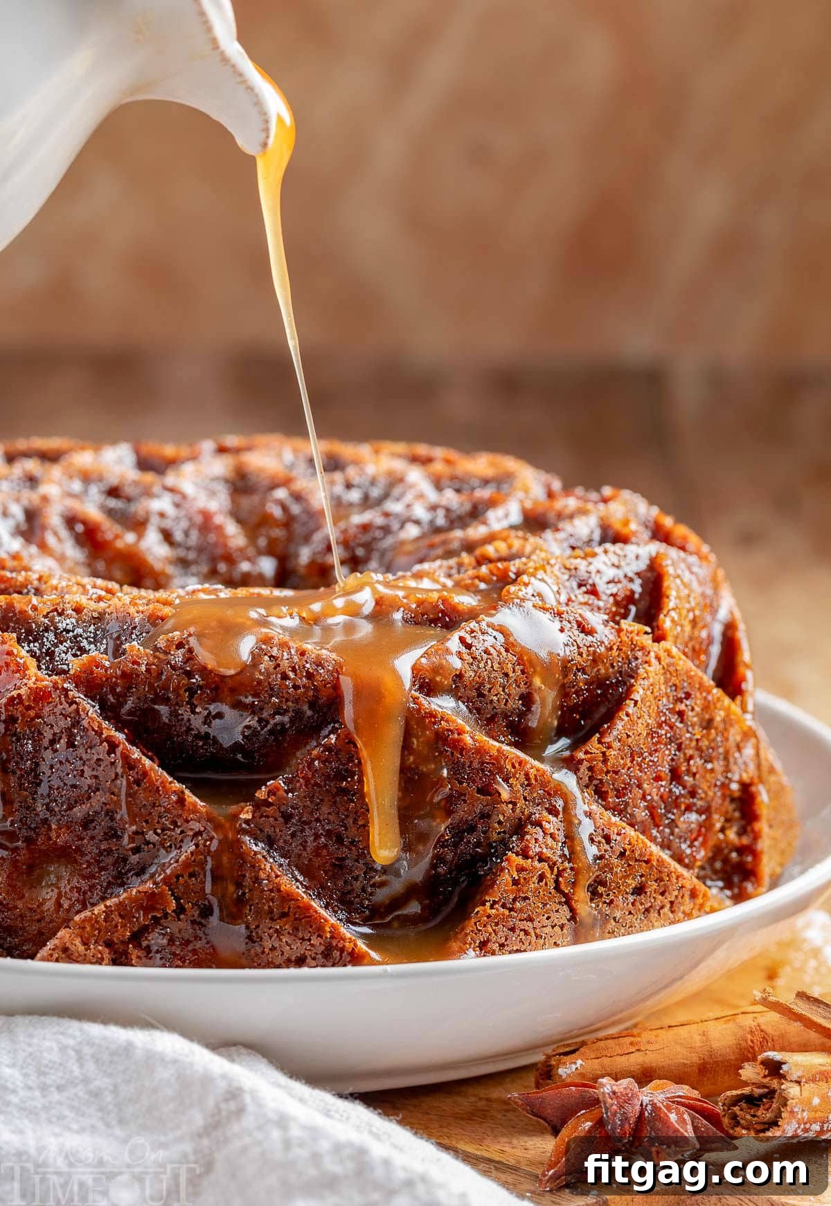 A mesmerizing shot of rich, golden caramel glaze being artfully drizzled over the intricate surface of a freshly baked Caramel Apple Bundt Cake. The glaze pools beautifully in the cake's contours, promising an explosion of sweet, buttery flavor with every bite.