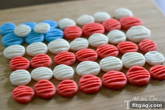 Red, White and Blue Peppermint Patties from MomOnTimeout.com - You pick the color and flavor! These patties are super easy to prepare and taste delicious! A hand reaching for a patriotic red, white, and blue candy patty, emphasizing their appeal.