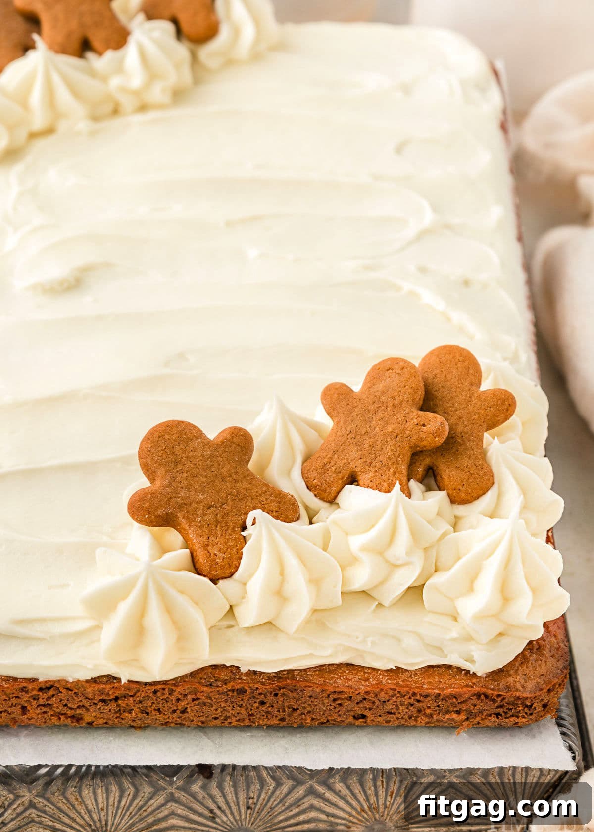 A side view of gingerbread cake topped with cream cheese frosting and gingerbread men.