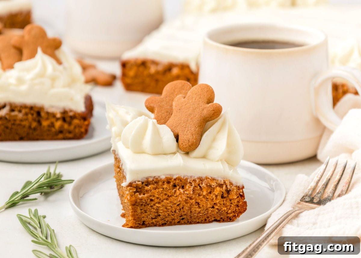 A slice of gingerbread cake topped with gingerbread men. The cake is on a white plate.