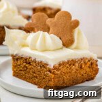 A slice of gingerbread cake topped with gingerbread men. The cake is on a white plate.