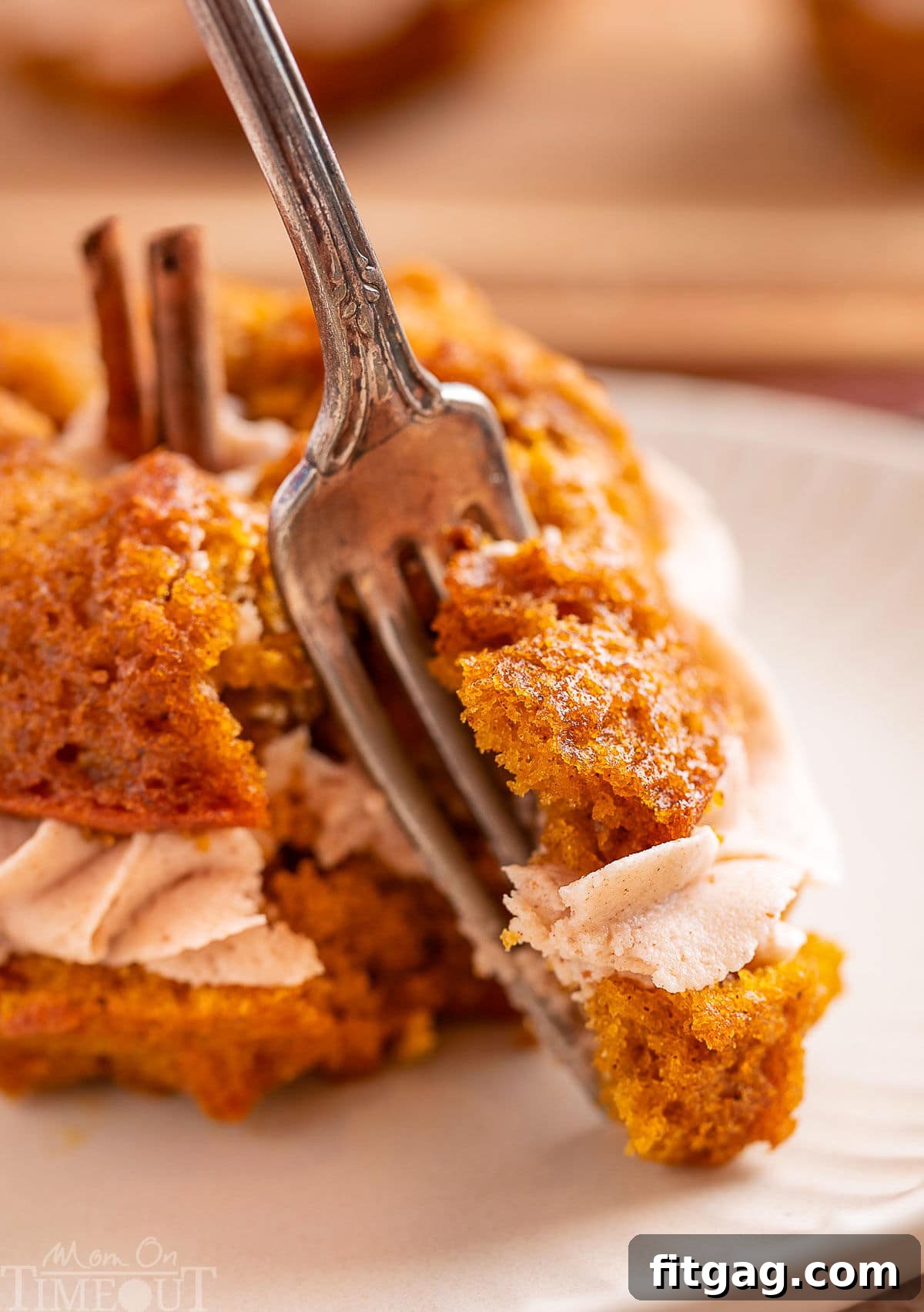 Forkful of pumpkin bundt cake being removed from the cake. Tender, moist cake and creamy frosting are shown on the fork.
