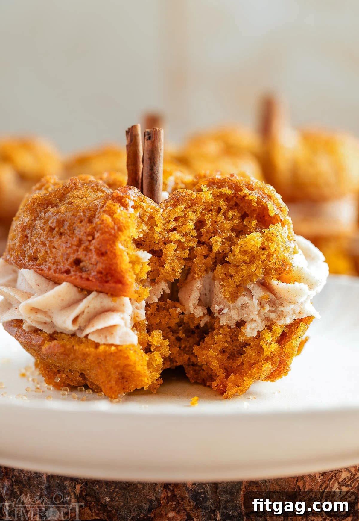 Pumpkin bundt cake on white round plate. Bite of the cake has been taken revealing the frosting layer between the two cakes.