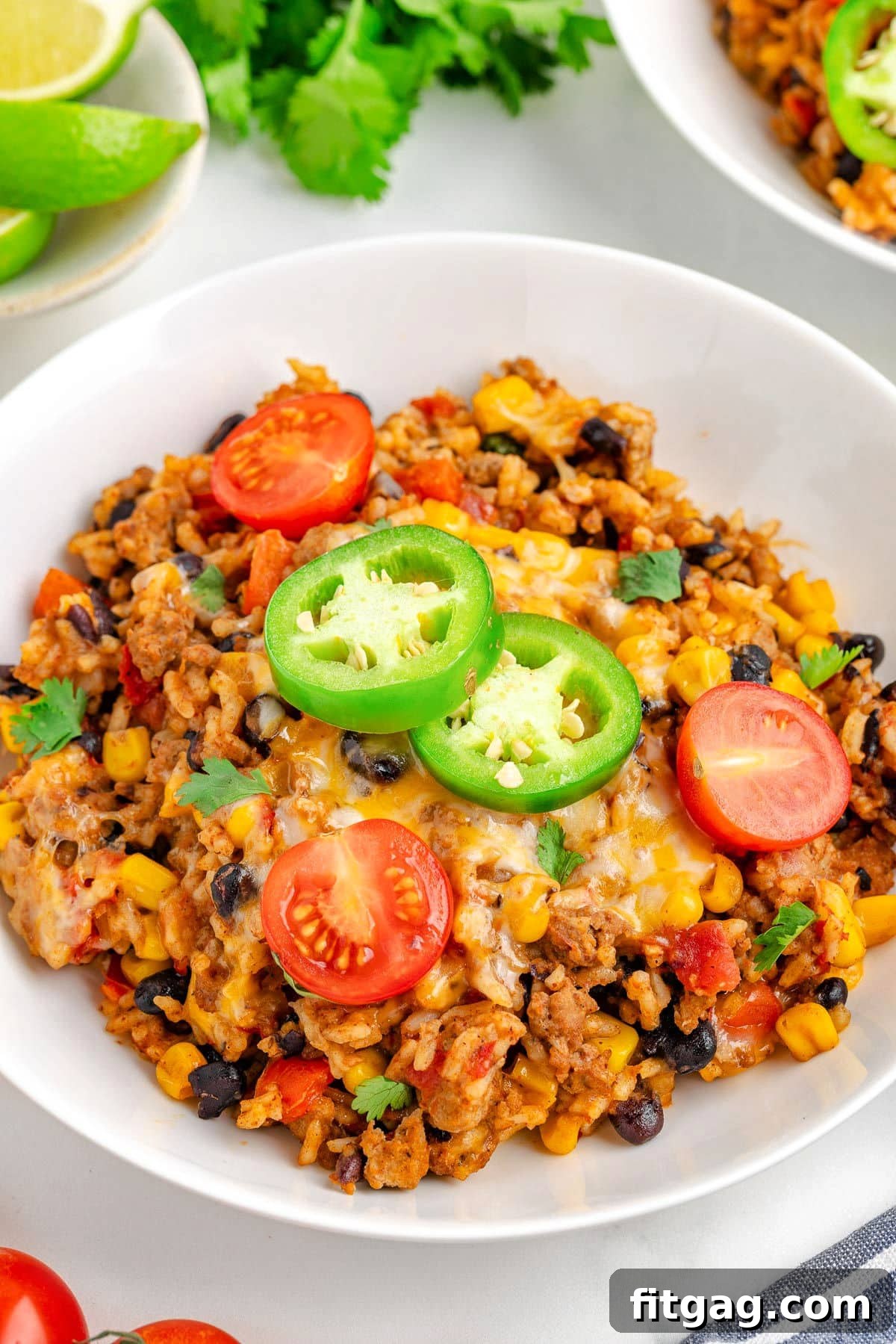 Ground turkey taco skillet rice in a white bowl topped with tomatoes and jalapenos. 