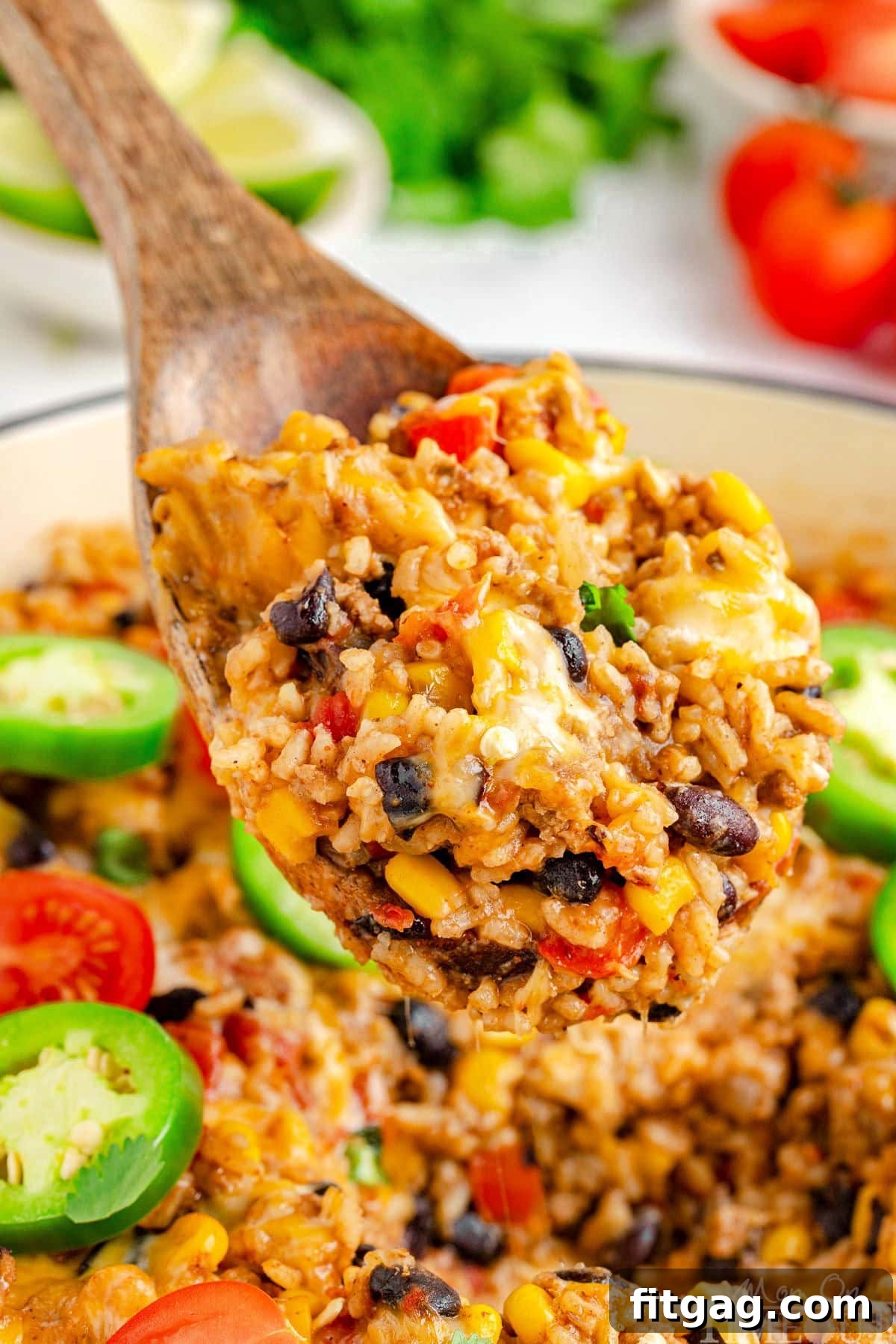 A wooden spoon delicately scooping out a generous serving of cheesy taco rice from a rustic white skillet, showcasing the rich texture and vibrant ingredients.