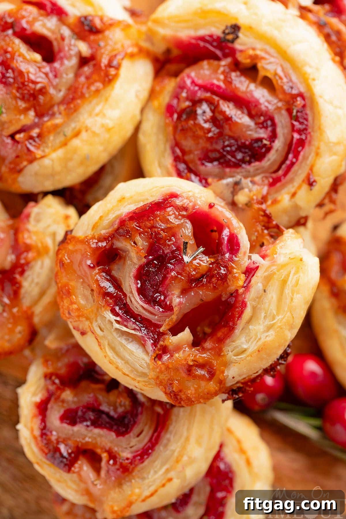 Festive Cranberry Brie Pinwheels 2 A top-down view of golden-brown Cranberry Brie Puff Pastry Pinwheels, perfectly stacked on an rustic wooden board, ready to be served as an elegant holiday appetizer.