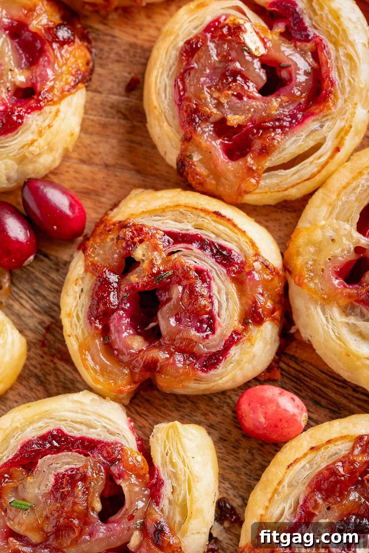 Festive Cranberry Brie Pinwheels 7 A vibrant top-down shot of perfectly baked Cranberry Brie Pinwheels arranged on a rustic wooden board, with fresh cranberries scattered nearby, ready for a festive holiday appetizer spread.