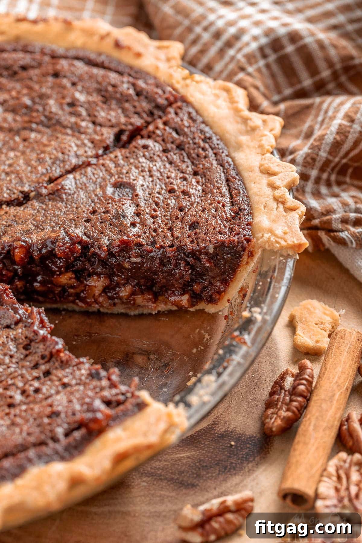 An inviting angled view looking down on a perfectly baked chocolate pecan bourbon pie with one slice neatly removed, showcasing its rich, gooey filling.