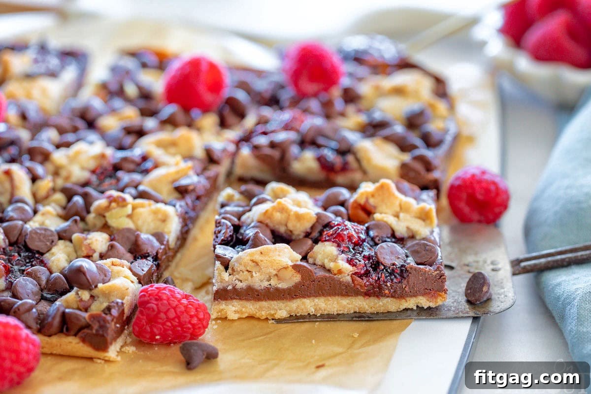 Decadent Raspberry Crumble Squares 7 Single bar being lifted away from the rest of the slab or bars on a cutting board.