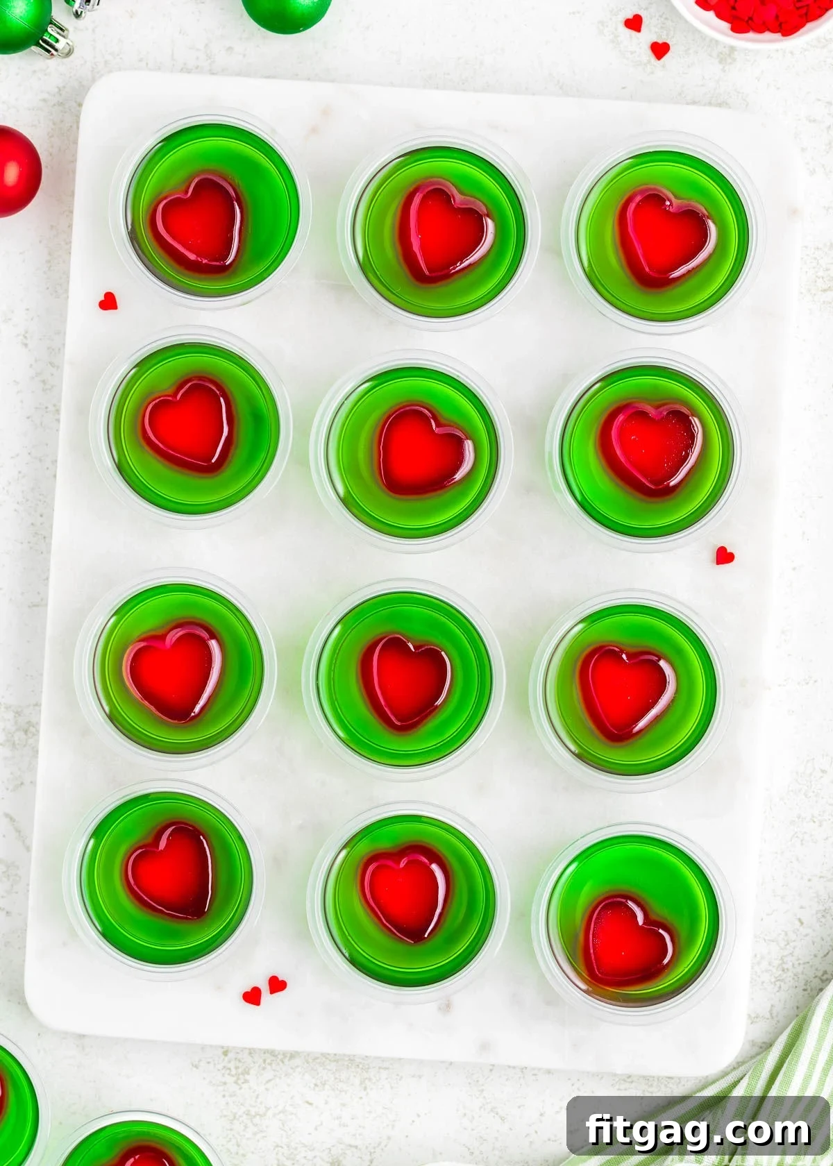 A top down view of Grinch Jello Shots lined up on a marble cutting board, ready for a Christmas party.