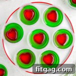 A top down view of grinch jello shots on a white plate with a red rim.