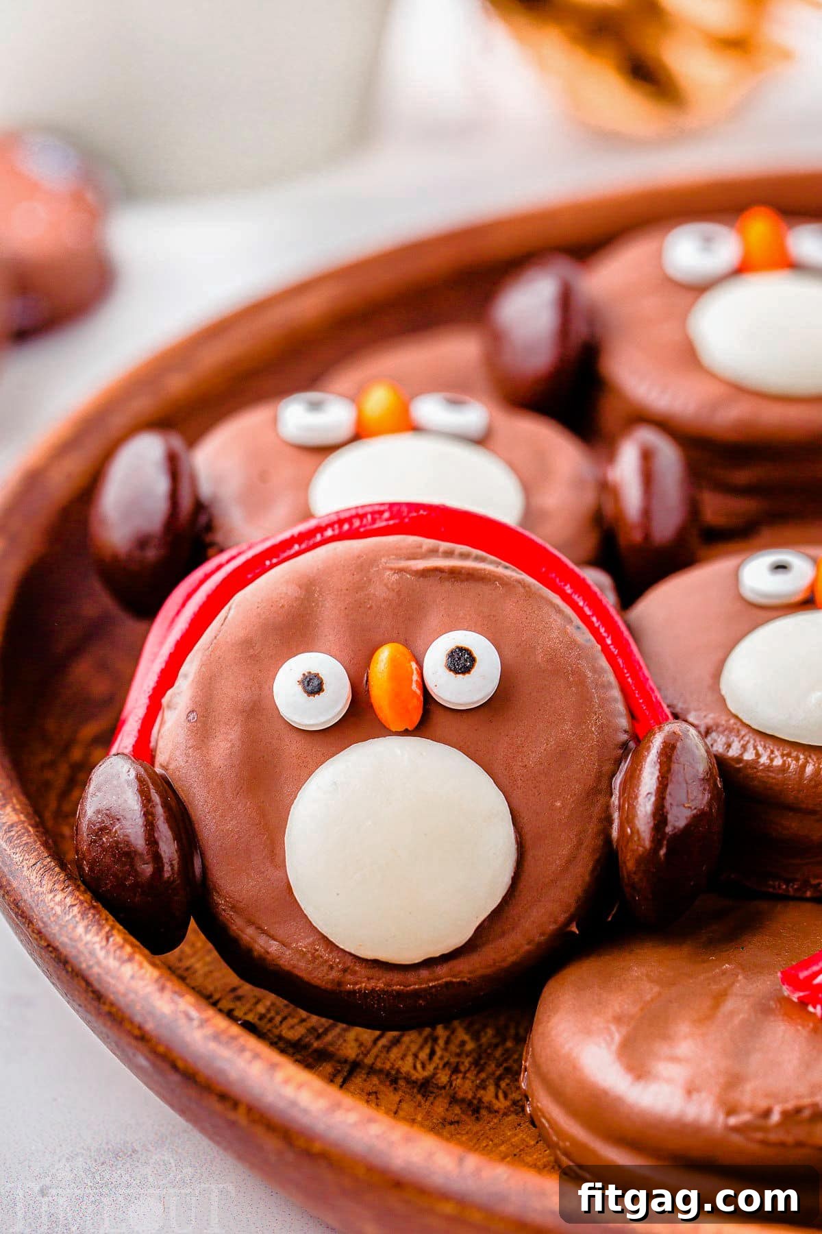 Arctic Oreo Treats 2 OREO Penguin propped up on a wood tray next to more penguin cookies. Penguin has red earmuffs.