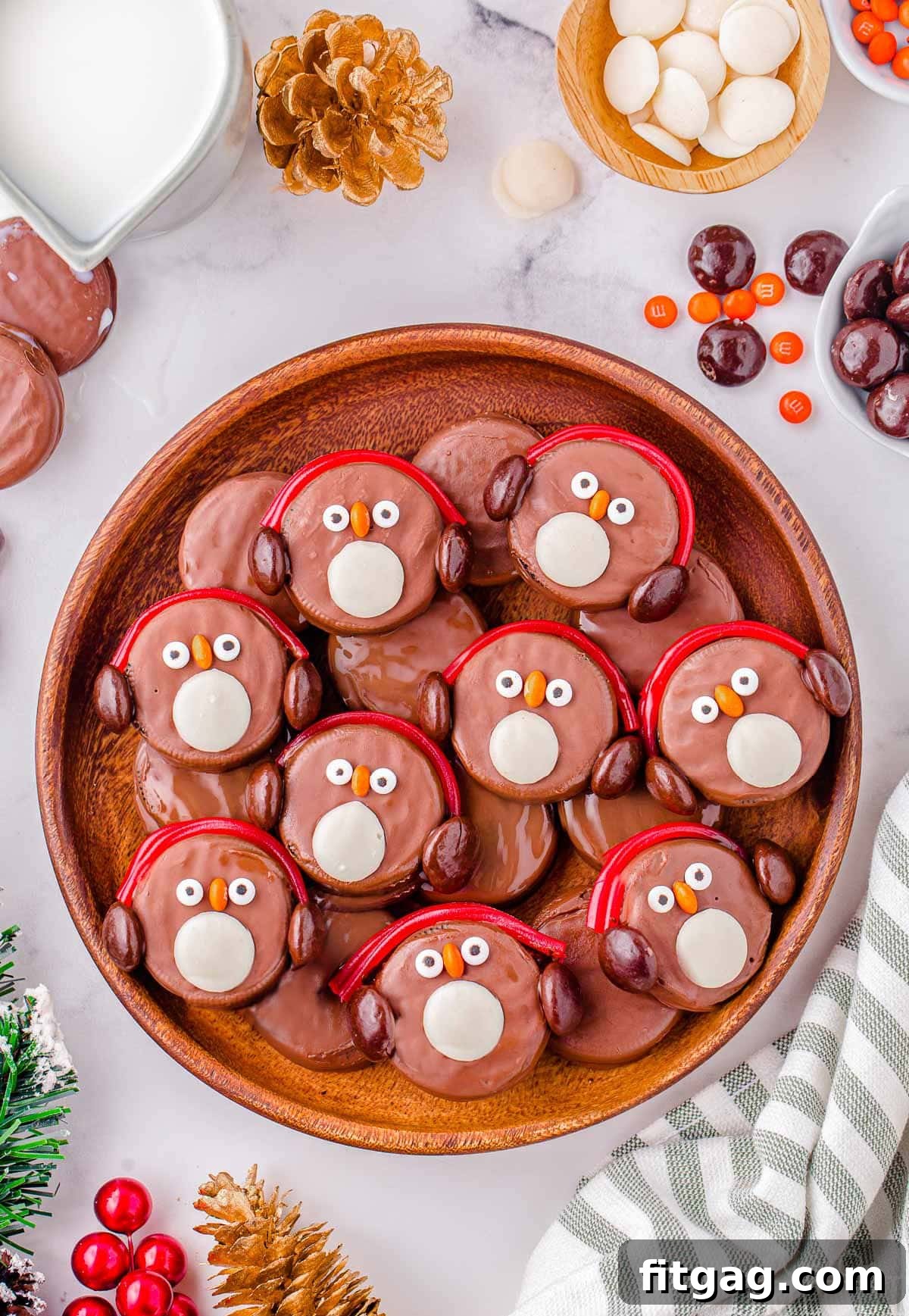 Arctic Oreo Treats 7 Top down shot of oreo penguins in a large round wood tray. Each penguin is decorated with red candy earmuffs.