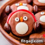 Arctic Oreo Treats 8 OREO Penguin propped up on a wood tray next to more penguin cookies. Penguin has red earmuffs.