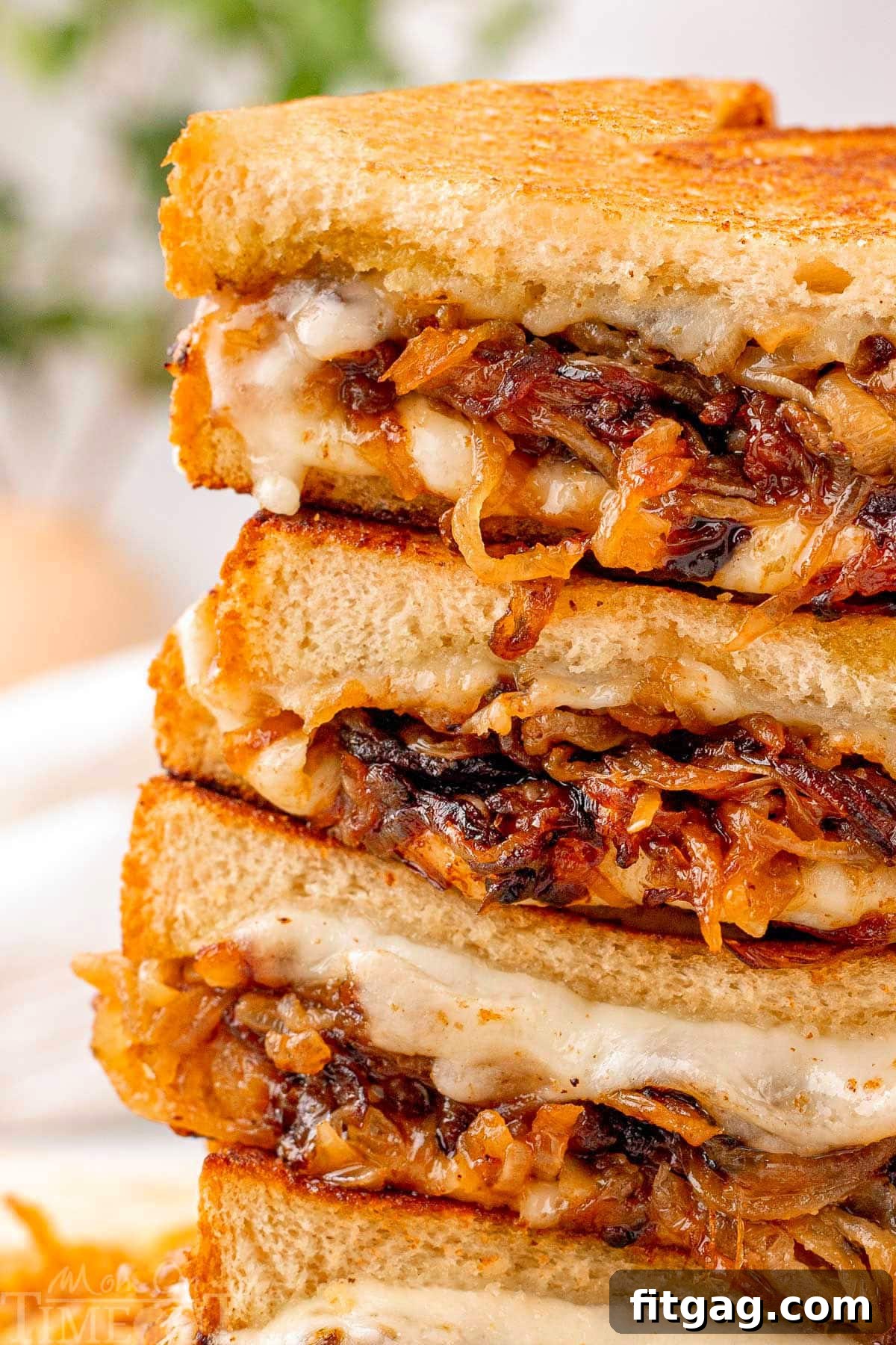 Close up look at caramelized onion grilled cheese cut in halve and stacked four high.