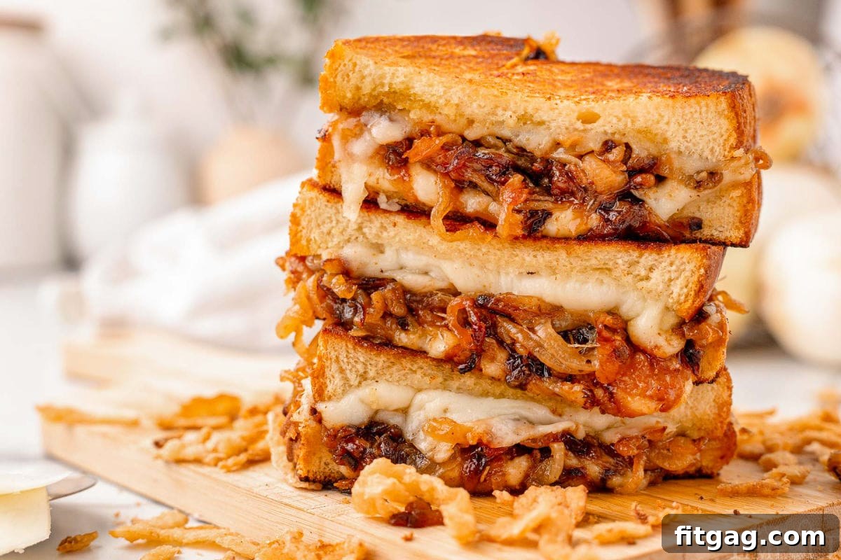 Wide shot of three halves of a french onion grilled cheese sandwich stacked on a wood cutting board with french fried onions surrounding it.